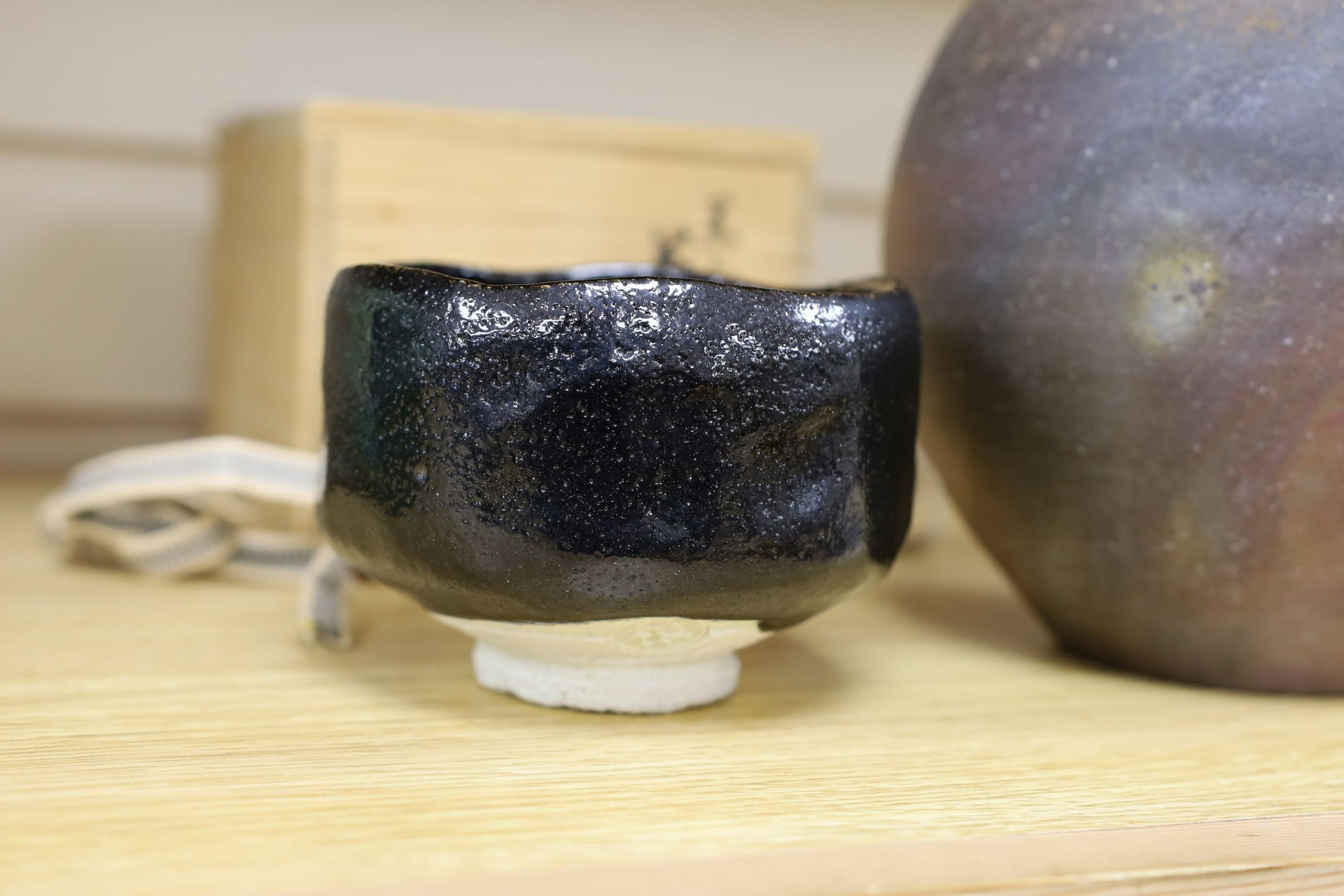 Japanese studio pottery: a boxed black glaze stoneware unomi tea bowl, with impressed mark, together with a ovoid vase, marked, 21cm tall